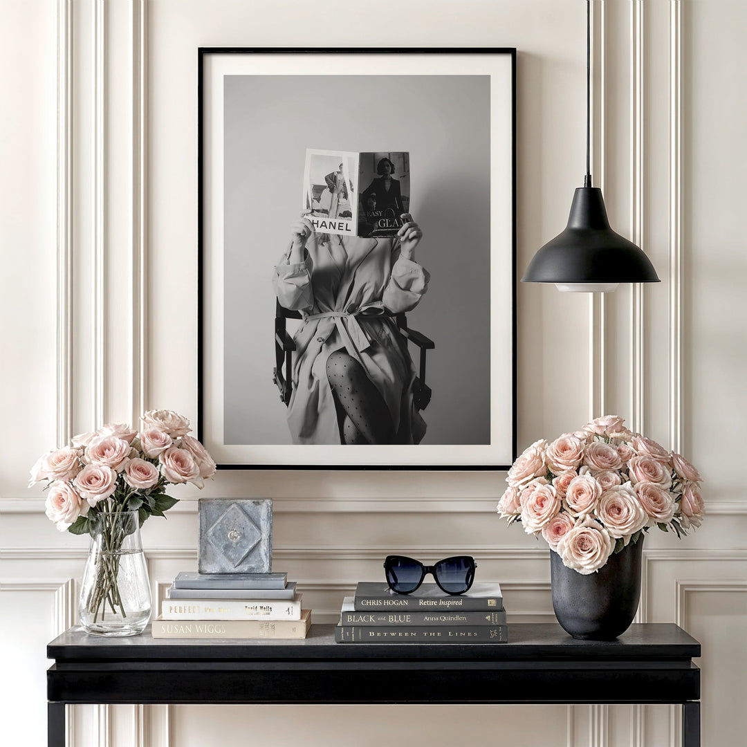 Modern canvas wall art with a black and white portrait of a woman holding a Chanel magazine above a console with roses.