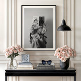 Modern canvas wall art with a black and white portrait of a woman holding a Chanel magazine above a console with roses.