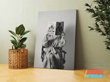 Motivational canvas wall art with a black and white woman in a director’s chair, a fashion magazine and an indoor plant.