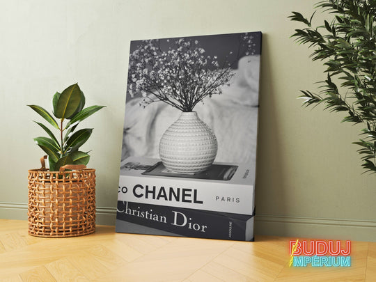 Luxury canvas print with black and white Chanel and Christian Dior book spines and a vase with dried flowers in an interior