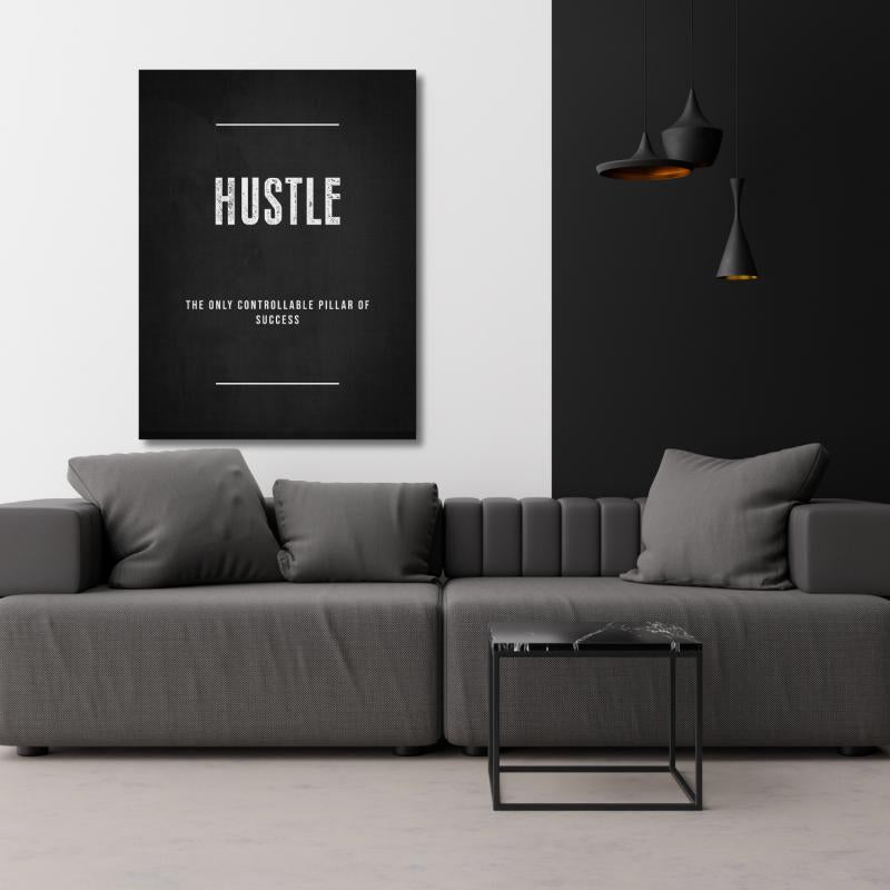 HUSTLE motivational canvas print in a modern living room with a gray sofa and black pendant lights.