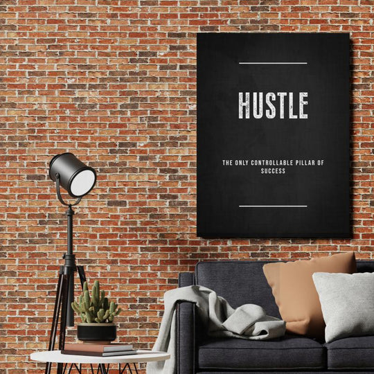 HUSTLE motivational wall art with a quote in an industrial interior with a brick wall, sofa and floor lamp.