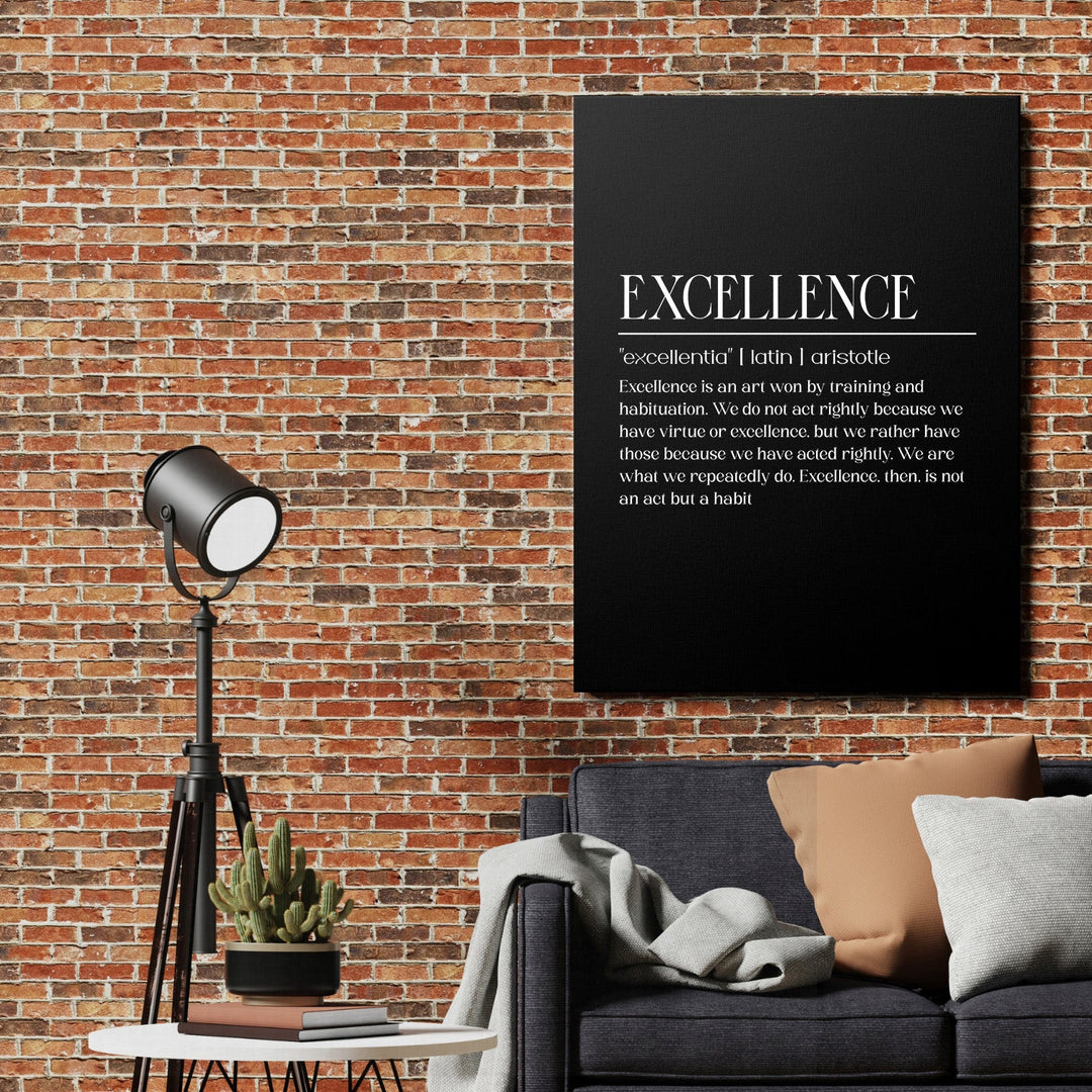 Excellence motivational canvas wall art above a sofa and lamp beside a brick wall
