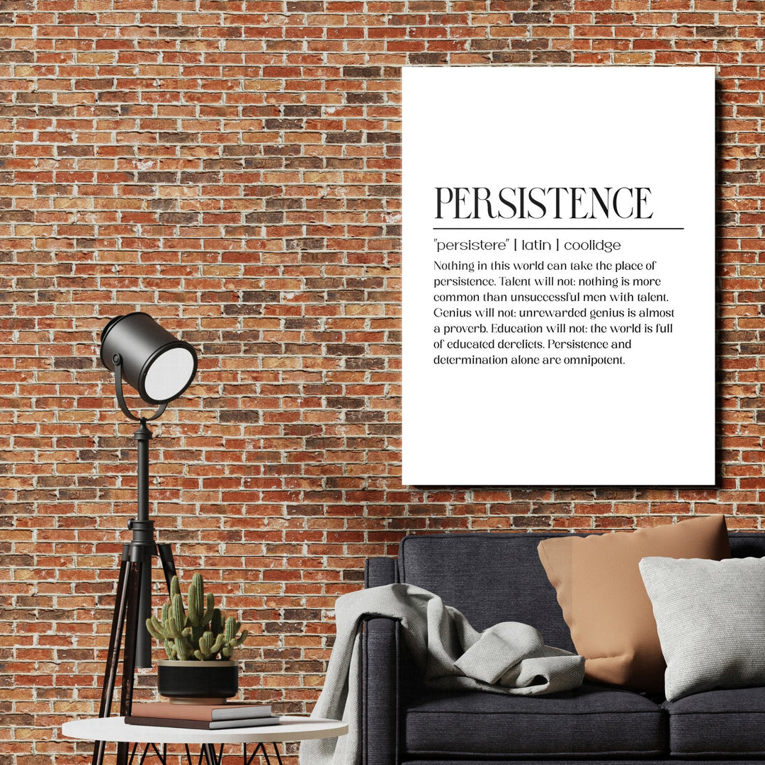 Persistence motivational canvas print on a brick wall in a living room with a lamp and cactus
