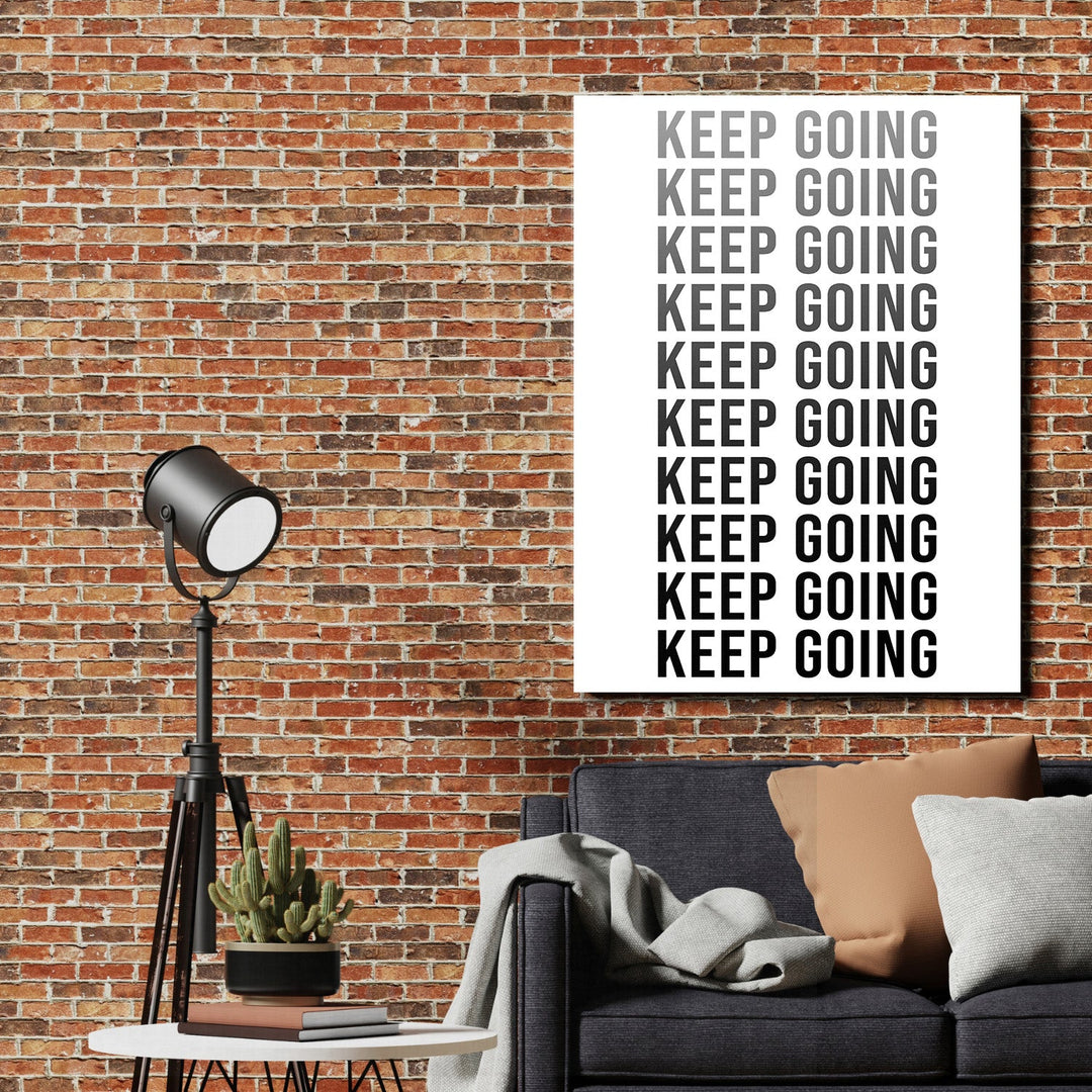KEEP GOING motivational wall art on a brick wall above a sofa in a modern interior