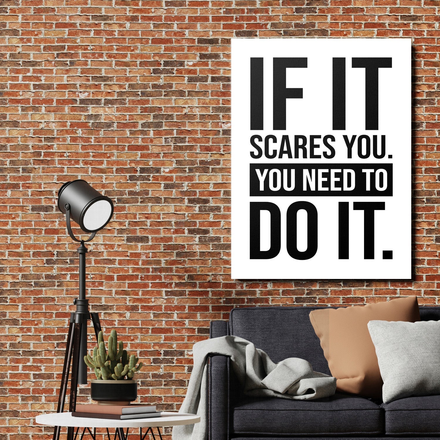 Motivational canvas print with a black-and-white quote on a brick wall in an industrial living room with a designer floor lamp