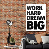 WORK HARD DREAM BIG motivational canvas wall art in an industrial interior above a dark gray sofa