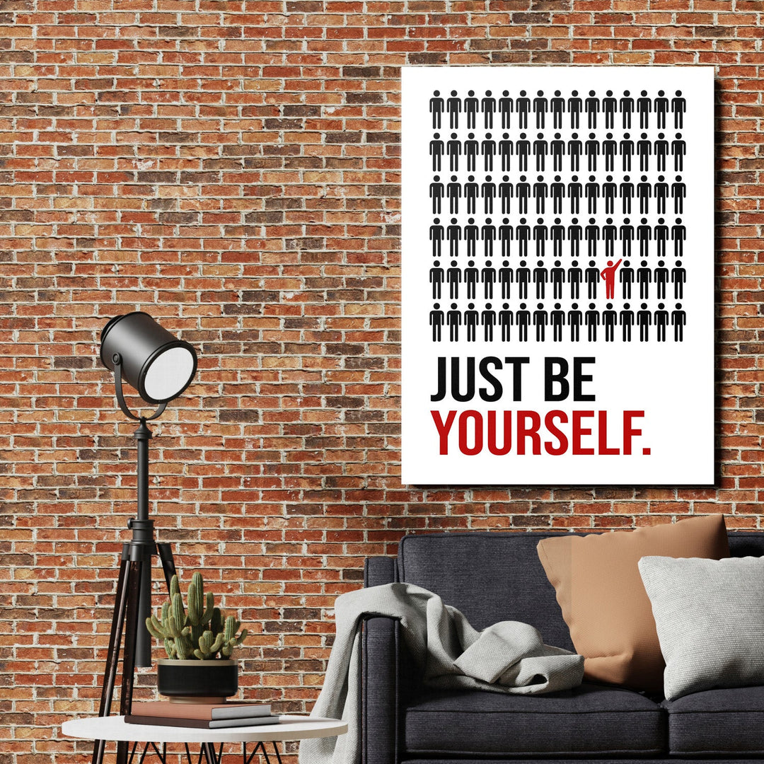 Motivational wall art in a loft interior with black pictograms and one red figure near the “JUST BE YOURSELF” text