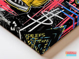 Corner detail of motivational canvas wall art with the graffiti text Hustlers Ambition in neon colors.