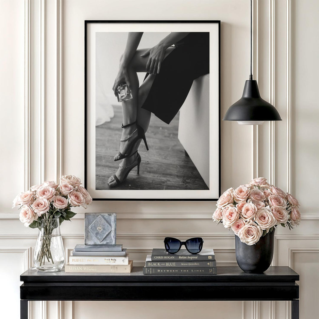 Luxury wall art with a black and white photograph of women’s legs in heels and Chanel perfume on a console