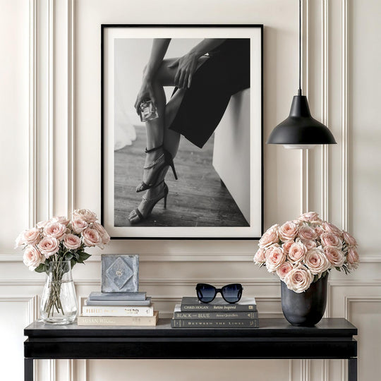 Luxury wall art with a black and white photograph of women’s legs in heels and Chanel perfume on a console