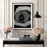 Modern wall art with a black and white photograph of a luxury handbag in an interior above fresh flowers