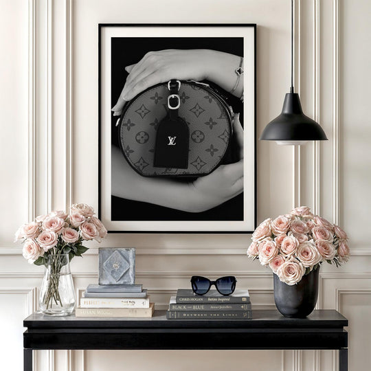 Modern wall art with a black and white photograph of a luxury handbag in an interior above fresh flowers