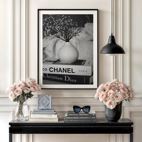Modern wall art with a black and white photograph of a vase on Chanel and Dior books in a living room