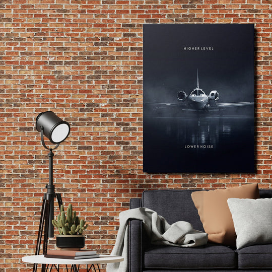 Motivational canvas print with an airplane and the texts “Higher Level” and “Lower Noise” on a brick wall above a sofa
