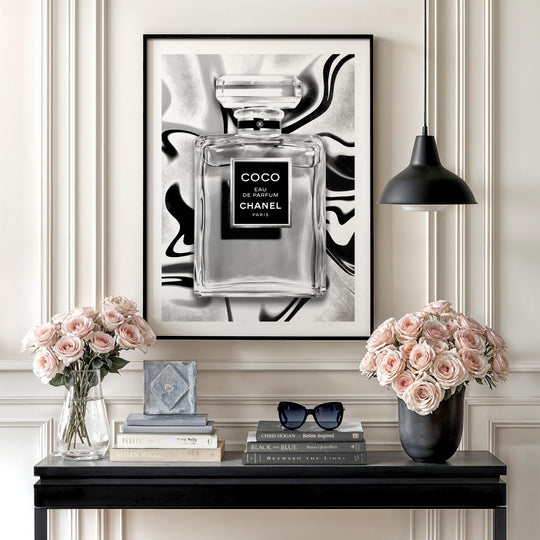 Motivational wall art with a black and white perfume bottle illustration, roses, books and a table lamp in a lifestyle arrangement.
