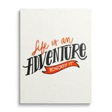 Motivational canvas print with the black-and-orange phrase “Life is an adventure – enjoy it”, front view