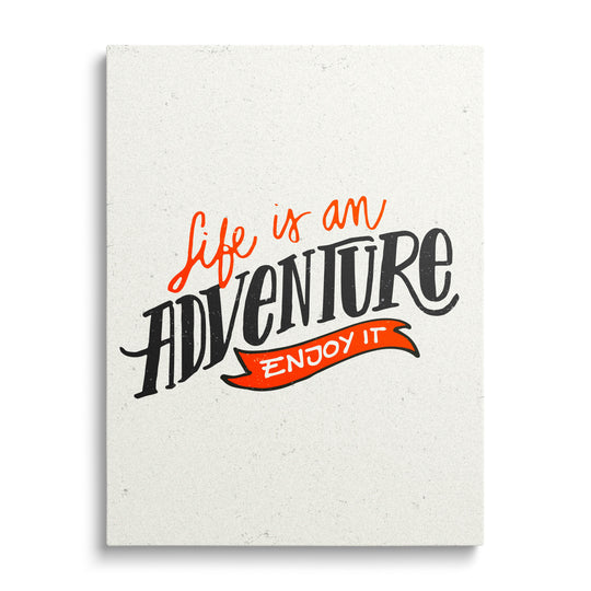 Motivational canvas print with the black-and-orange phrase “Life is an adventure – enjoy it”, front view