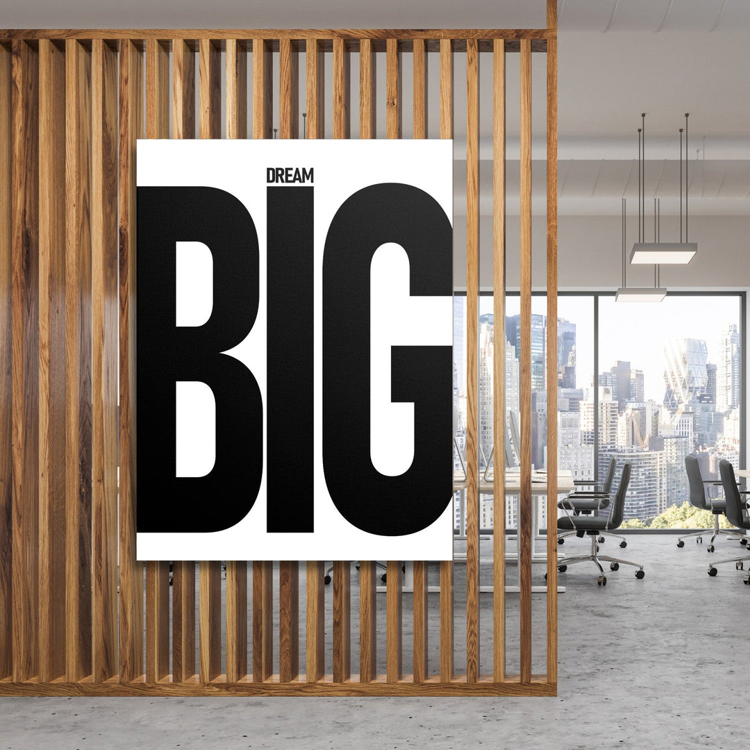 DREAM BIG motivational canvas wall art with black typography in a modern office behind a wooden grid