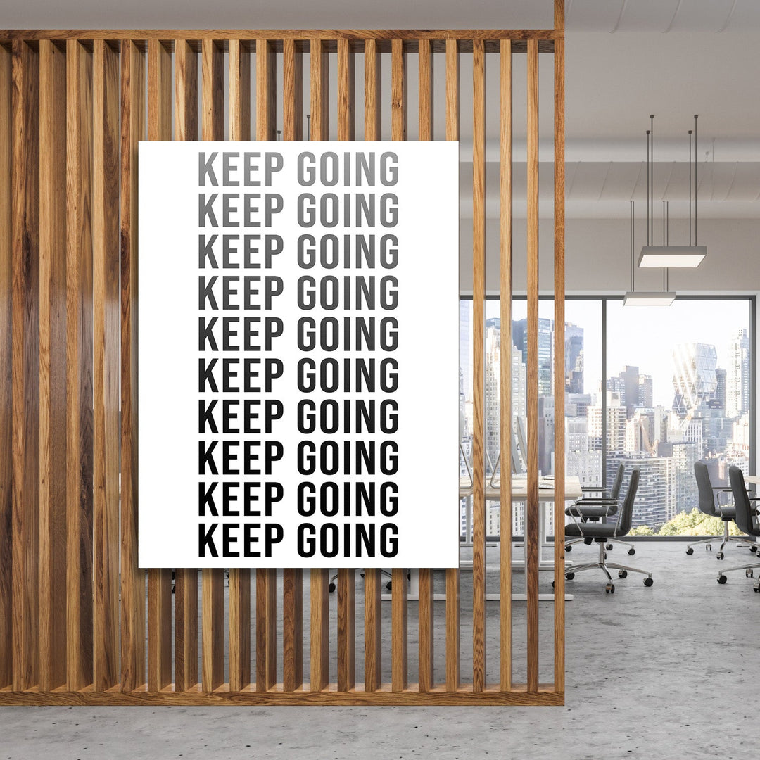 Black and white Keep Going motivational wall art with repeated text in a modern office