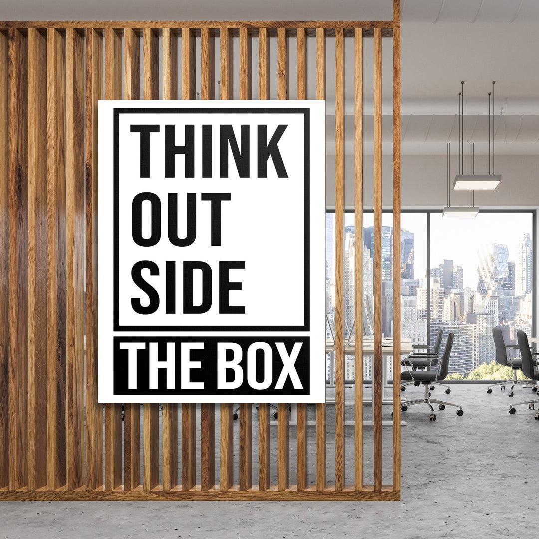 Motivational canvas print with a “Think outside the box” quote in a modern office behind a wooden partition