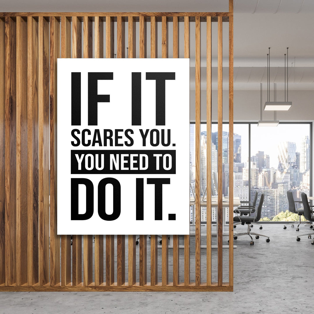 Motivational canvas print with a black-and-white quote hanging on wooden slats in a modern office