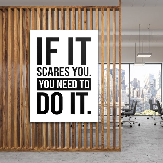Motivational canvas print with a black-and-white quote hanging on wooden slats in a modern office