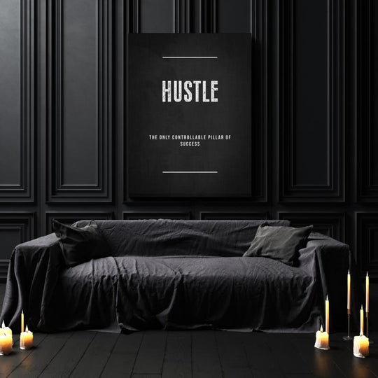 HUSTLE motivational canvas print in a dark interior above a black sofa and burning candles.
