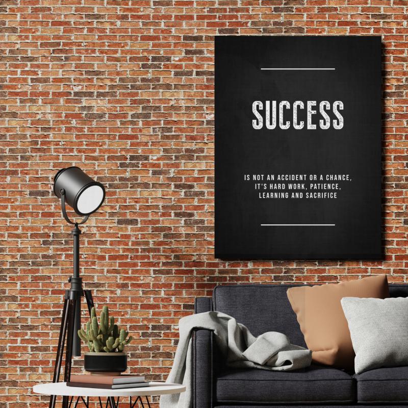 Success motivational canvas print on a brick wall in a living room above a sofa with a floor lamp.