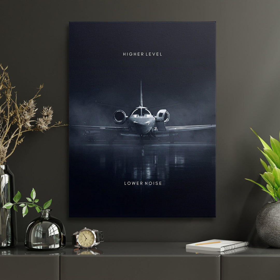 Motivational wall art with a luxury private jet and the text “Higher Level, Lower Noise” in a modern office