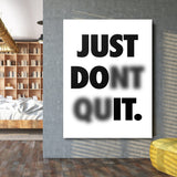 Motivational canvas wall art in a living room with a minimalist black and white quote and slightly blurred lower line