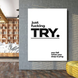 Motivational wall art with a black-and-white minimalist “just fucking TRY” quote in an industrial interior