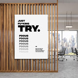 Black and white “Just Fu*king Try. Focus…” motivational canvas print hanging in a modern office.