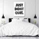 Black and white motivational quote wall art above a bed in a minimalist bedroom