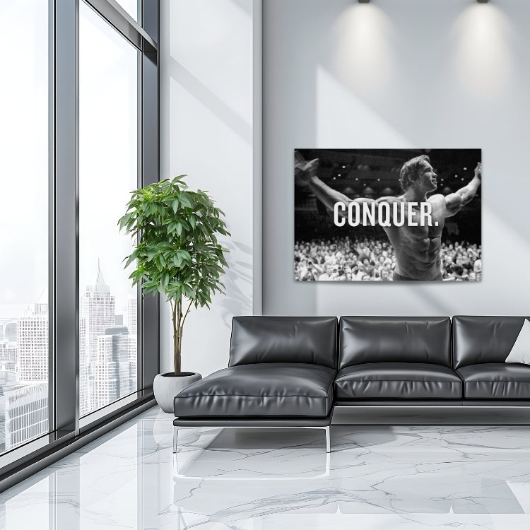 Motivational wall art with a black and white bodybuilder raising his arms and CONQUER text in a modern living room.