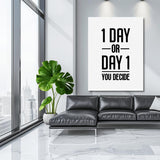 Motivational wall art with black-and-white “1 DAY OR DAY 1” typography in a modern living room with a leather sofa.